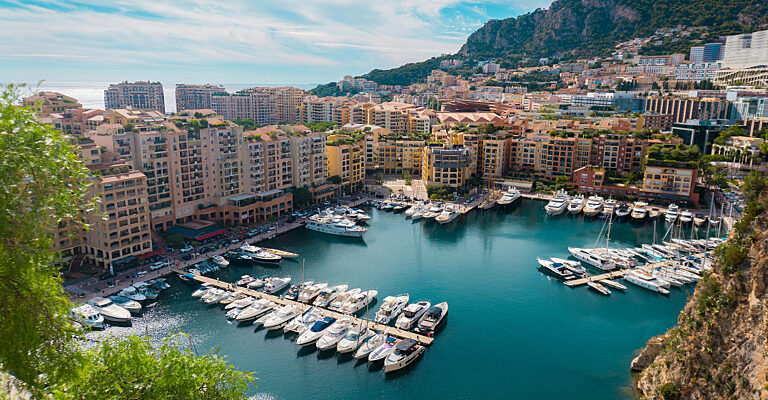 Blick auf den Hafen von Fontvieille in Monaco mit zahlreichen Yachten und der terrassenförmigen Bebauung am Berghang.