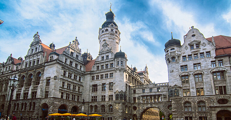 Das Neue Rathaus in Leipzig mit seinem markanten Turm und den historischen Fassaden unter blauem Himmel.